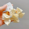 Détail du nœud papillon en tissu beige avec bords ondulés sur carte de présentation - Chouchou beige