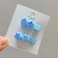Close-up of blue sequin flower hair clips with soft fur balls and fabric-wrapped duckbill clips - Light Blue Style