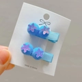 Close-up of blue pompom hair clips with sequin flowers on a white display card - Sky Blue Style