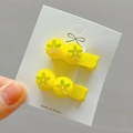 Close-up of yellow hair clips with green flower ornaments and fabric wrapped metal body - Bright Yellow Style