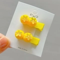 Detailed view of yellow plush pom-pom hair clips with flower sequins on white card - Golden Style