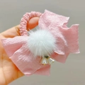 Dettaglio di un fiocco per capelli rosa con pompon bianco e ciondolo a fiorellino - Elastico Fiocco Rosa Coreano