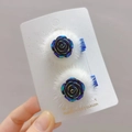 Gros plan de barrettes à cheveux rose en résine lumineuse avec fausse fourrure blanche - Paire de Roses Bleu-noir Lumineuses