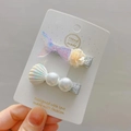 Detalle de pinzas para el cabello con cola de sirena y concha con perlas - Morado Y Blanco