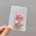 Gros plan sur barrettes à fleurs rose pailletées avec perles sur carte décorative - Pince Bec de Canard Rose