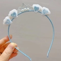 Close-up of white plush pom-poms with blue hearts and a silver crown on a blue headband - White + Blue