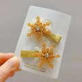 Détail de deux barrettes flocon dorées avec paillettes et strass sur une carte de support - Doré