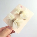 Zwei cremefarbene Tüll-Haarspangen mit goldenem Glitzer auf einer Displaykarte - Beige