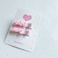 Close-up of handmade pink satin rose hair clips for girls on a white cardboard card - Light Pink Pair