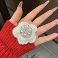 Dettaglio macro di un fiore lavorato a maglia bianco con perle e strass centrali - Modello con Perle