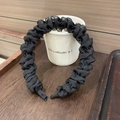 Detalle de una diadema plisada negra estilo scrunchie mostrada sobre una taza blanca - Negro