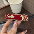Detail einer roten Haarspange aus Samt mit goldenem Pferd und Smile-Schriftzug - Schmaler Clip - Ji Pferd