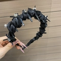 Dettaglio del cerchietto gotico nero con strass e fiocco su sfondo di legno naturale - Nero