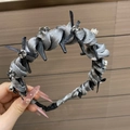 Dettaglio del cerchietto in tessuto intrecciato argento con strass e fiocco nero - Grigio