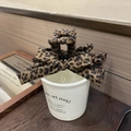 Detail view of a vintage leopard print bow hair claw clip placed on a white coffee mug - Leopard Style