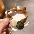 Detalle de una goma de pelo trenzada marrón con perla beige mate y una bola verde - Caqui