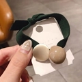 Primer plano de una goma de pelo verde con cuentas doradas y caqui en tarjeta - Verde