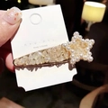 Dettaglio di un fermaglio per capelli a stella con strass e perle su cartoncino bianco - Bianco