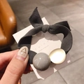 Detalle de coletero de tela gris oscuro con lazo y disco dorado sobre cartulina - Gris