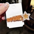 Close-up of star hair clip with amber texture and pearls on a branded card - Champagne