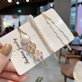 Dettaglio macro di un set di tre fermagli per capelli dorati con perle e cristalli misti - Stile bianco