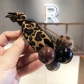 Close-up of leopard print hair tie with plush pom-pom and assorted decorative beads - Black