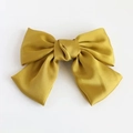 Macro shot of large yellow satin bow hair clip showing smooth texture and fabric details - Yellow