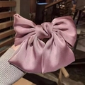 Detail of a large dusty pink satin bow hair clip with elegant layered fabric texture - Pink