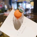 Détail d'une mini pince à cheveux en forme d'orange avec texture en résine et feuilles vertes - Orange