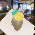 Gros plan d'une pince à cheveux ananas en résine pailletée avec ressort argenté sur carte - Ananas