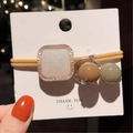 Detail of yellow elastic hair tie featuring a square pearlescent charm and colorful beads - White Jade Square Ornament (White Jade)
