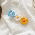 Close-up of three daisy flower hair clips in blue, white, and yellow on knit background - Blue White Yellow Daisy Combo