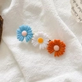 Detailed shot of cute resin daisy hair clips in blue, white, and orange on fabric - Blue White Orange Daisy Combo