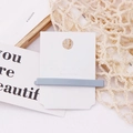 Detailed macro view of a matte grey Morandi hair clip on a white Korean display card - Gray