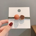 Detailweergave van Morandi haarelastiek met matte oranje kraal en bruin metalen accent - Oranje