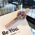 Elegante fermaglio dorato con cristalli colorati e strass rosa su un biglietto bianco - Viola