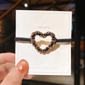 Detailed close-up of a heart-shaped chain hair scrunchie with woven leather texture - Heart Style
