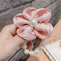 Close-up of pink satin flower hair clip with central pearl and small pearl beaded string - Pink