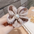 Détail d'un chouchou fleur en satin champagne avec un ornement en perle blanche - Champagne