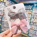 Close-up of pink floral and solid fabric bow hair clips on a white display card - Pink Floral and Solid Pink