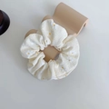 Détail d'un chouchou crème avec imprimé marguerites sur tissu à texture douce - Blanc