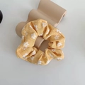 Detailed close-up of yellow floral scrunchie with white daisy print on white background - Yellow