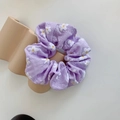Detail of purple floral scrunchie with white daisy print on a minimalist wavy display - Purple
