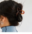Détail d'une pince à cheveux motif écaille marron tenant un chignon élégant - Ambre