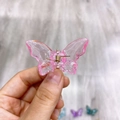 Nahaufnahme einer rosa transparenten Schmetterlings-Haarklammer mit Goldfeder - Rosa
