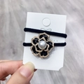 Detail showing two black camellia hair ties with faux pearl edges and elastic bands - Black