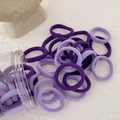 Macro shot of purple high-elastic seamless hair ties in a clear jar on stone background - Purple