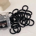 Detail of high-elasticity seamless black hair ties stored in a clear cylindrical jar - Black