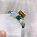 Dettaglio di un fermaglio per capelli dorato con perle in resina marmorizzata blu e verdi - Blu Oro