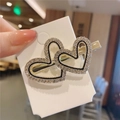 Detailed view of golden heart-shaped hair clip with inlaid rhinestones and black enamel - Heart Zirconia